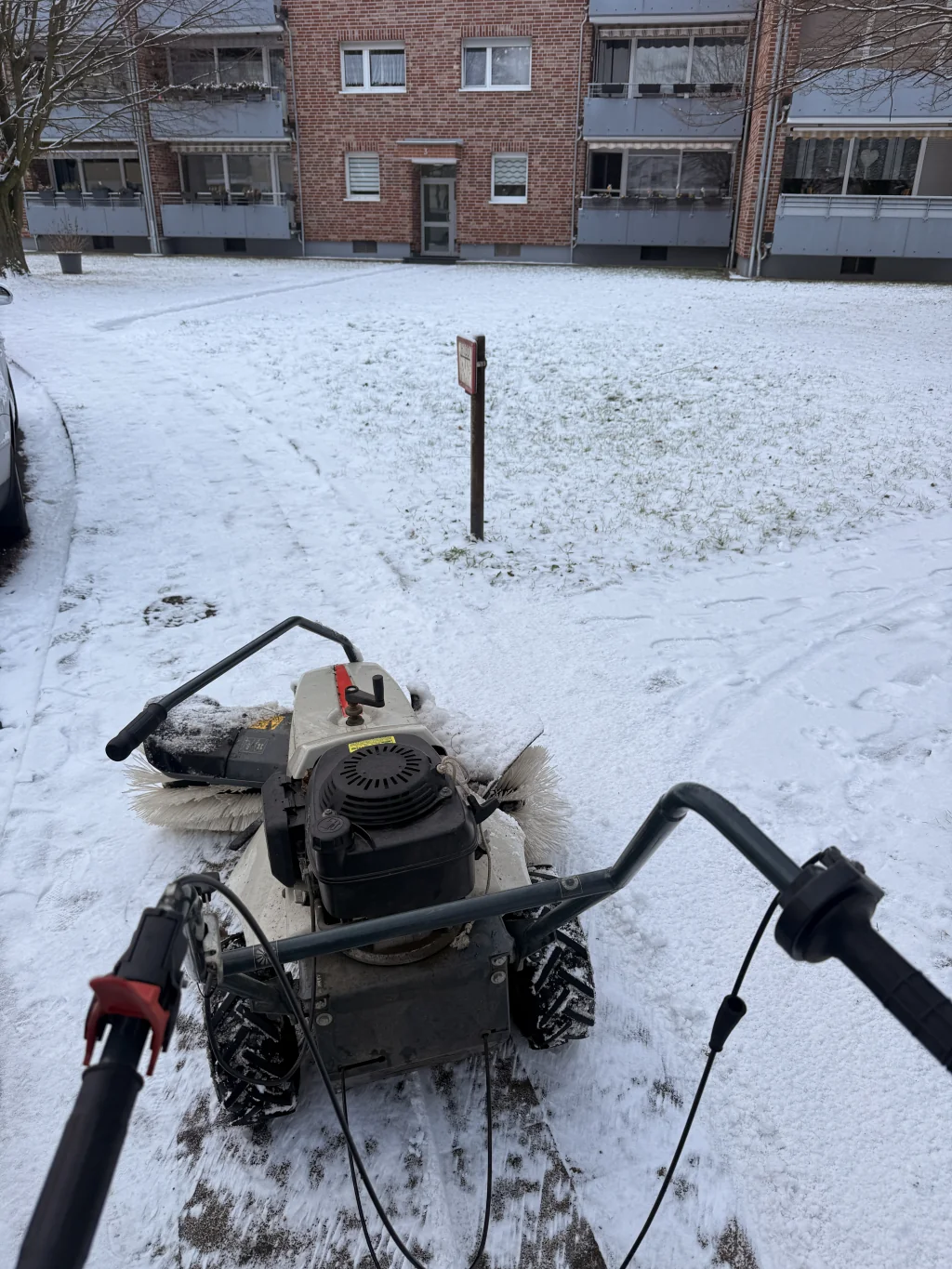 Winterdienst: Schneefräse im Einsatz vor einer Wohnanlage